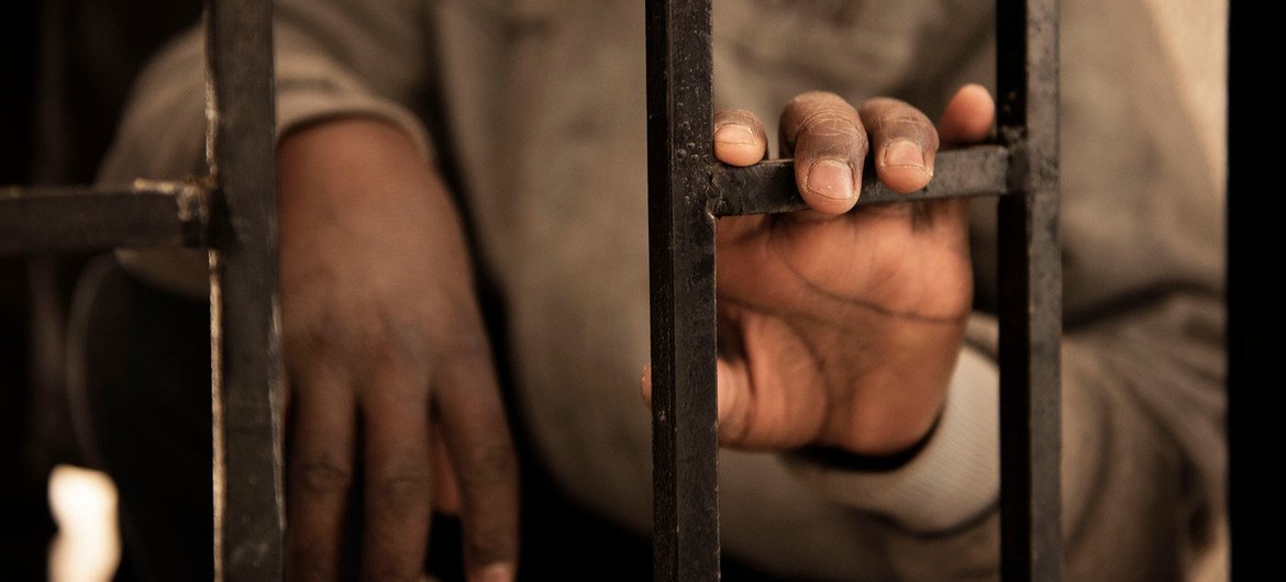 © UNICEF/Alessio Romenzi | صبي مهاجر من النيجر عمره 14 عاما يضع يده على باب مركز احتجاز في ليبيا.
